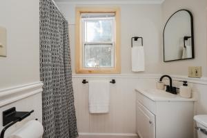 a white bathroom with a shower curtain and a sink at EverHaus Cabin by the Brook - Harvard Brook Cabins in Lincoln +12 photos
