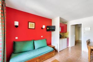 - un salon avec un canapé vert et un mur rouge dans l'établissement La résidence du Lac - maeva Home - Appartement 2 pièces 5 personnes - Conf 454, à Monflanquin
