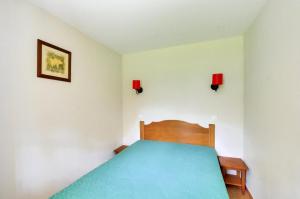 - une chambre avec un lit bleu et deux lumières rouges dans l'établissement La résidence du Lac - maeva Home - Appartement 2 pièces 5 personnes - Conf 454, à Monflanquin