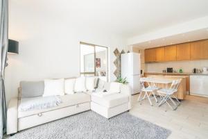 sala de estar con sofá blanco y cocina en Spacious 1 bed in Vilamoura, Fast Wifi & Pool, en Quarteira
