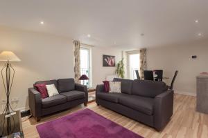 a living room with two couches and a tv at Glasgow City Flats in Glasgow