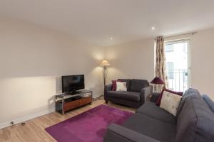 a living room with a couch and a tv at Glasgow City Flats in Glasgow