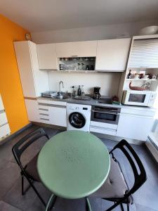 una piccola cucina con tavolo e sedie verdi di Le Birdy - maeva Home - Appartement 2 pièces 4 personnes - Prestige 614 a La Grande-Motte