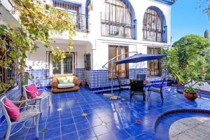 een patio met blauwe tegels en stoelen en een parasol bij Villa Jazminez by Villa Plus in Marbella