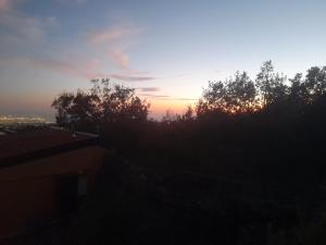 um pôr-do-sol sobre uma colina com árvores e uma cidade em Etna Country Home em Nicolosi