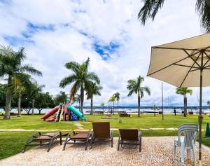 Life Resort, Beira Lago Paranoá في برازيليا: حديقة بها كراسي ومظلة وملعب