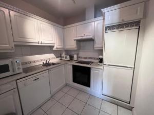 a white kitchen with white cabinets and a refrigerator at The Canal View in Dublin