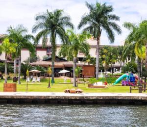a view of a resort from the water with palm trees at Life Resort, Beira Lago Paranoá in Brasilia