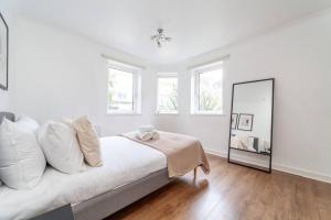 a white bedroom with a bed and a mirror at Stylish 3-bed near Camden Town & King's Cross in London