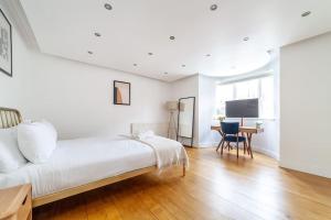 Habitación blanca con cama grande y escritorio. en Stylish 3-bed near Camden Town & King's Cross en Londres