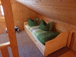 Bett in einem Blockhaus mit grünen Kissen in der Unterkunft Ferienhaus Obert - Drognitz in Drognitz