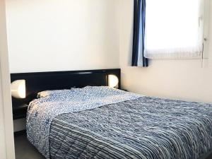 een slaapkamer met een bed met een blauw dekbed en een raam bij Résidence Le Boucanier - 2 Pièces pour 4 Personnes 084 in Vieux-Boucau-les-Bains