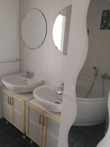 une salle de bain avec deux lavabos, une baignoire et un miroir dans l'établissement Appartement accueillant au cœur de Le Conquet avec parking privé, au Conquet