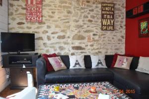 ein Wohnzimmer mit einem schwarzen Sofa und einer Steinmauer in der Unterkunft Propriete de 2 chambres avec wifi a Saint Pol de Leon a 1 km de la plage in Saint-Pol-de-Léon