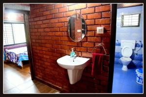 a brick walled bathroom with a sink and a toilet at Tiny Waves in Udupi