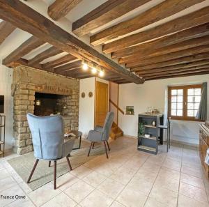 sala de estar con chimenea de piedra y silla en Le p’tit Suisse Normand en Putanges