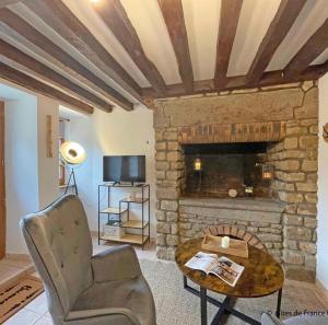 sala de estar con chimenea, silla y mesa en Le p’tit Suisse Normand en Putanges