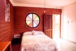1 dormitorio con cama y ventana redonda en Daya Ma Hospedagem en Alto Paraíso de Goiás