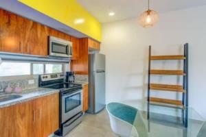 uma cozinha com armários de madeira e um forno com placa de fogão em Condo Complex with an Alluring Pool & Tropical Vibes by Stella Rentals em Tulum