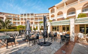 eine Hotelterrasse mit Tischen, Stühlen und Sonnenschirmen in der Unterkunft Résidence les Calanques des Issambres - maeva Home - Appartement 2 pièces 4 personnes - Sélection MAE-3624 in Les Issambres