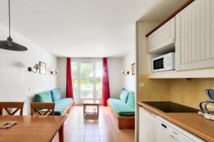uma cozinha e sala de estar com sofás azuis em La résidence du Lac - maeva Home - Appartement 2 pièces 5 personnes - Sél 674 em Monflanquin