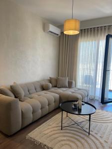 uma sala de estar com um sofá grande e uma mesa em Square INN Garden Aparthotel em Tirana