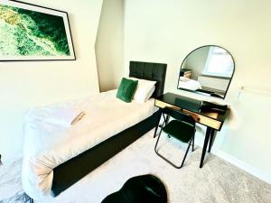 1 dormitorio con cama con espejo y escritorio en Stone Villas By Alternative Stays en Hednesford