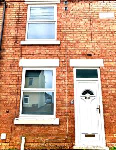 a brick building with a white door and two windows at Stone Villas By Alternative Stays in Hednesford