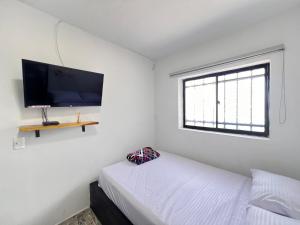 Schlafzimmer mit einem Bett und einem Flachbild-TV in der Unterkunft Nativos Hospedaje in Medellín