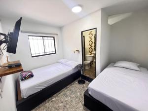 2 camas en una habitación pequeña con espejo en Nativos Hospedaje, en Medellín