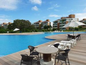 a pool with tables and chairs next to a building at Apartamento Térreo no Catu Lake Resort Aquiraz in Aquiraz