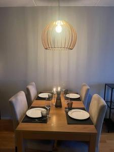 una mesa de madera con sillas y una lámpara. en Leilighet i Tromsø, en Tromsø 16 fotos más