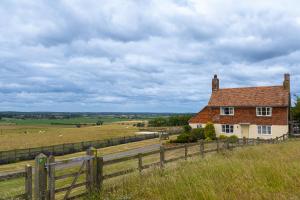 a house on the side of a field with a fence at Coldharbour Cottage with Hot Tub in Stone
