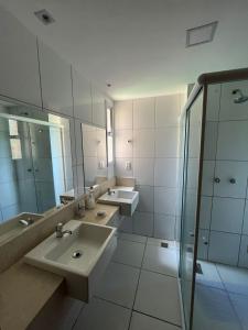 baño con 2 lavabos y ducha de cristal en Apartamento Térreo no Catu Lake Resort Aquiraz en Aquiraz
