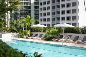 マイアミにあるAKA Brickell Luxury Residences Free Parkingの建物の隣にスイミングプール(椅子、パラソル付)