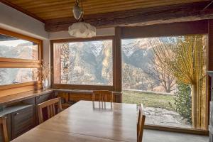 Casa Bubeck في Cavagnago: غرفة طعام مع طاولة ونافذة كبيرة