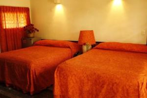 um quarto de hotel com duas camas com lençóis laranja em Villablanca Garden Beach Hotel em Cozumel