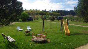 um parque com um parque infantil com um banco e um escorrega em Gite 3 étoiles - Piscine - eececf em Chamberet