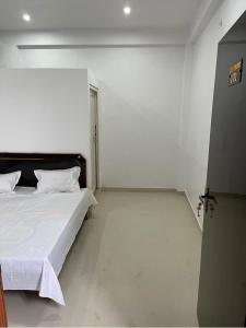 1 dormitorio con 1 cama en una habitación blanca en OYO Hotel Red Cross(banquet&restra) en Kānpur