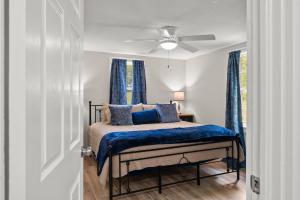 a bedroom with a bed with blue curtains and a ceiling fan at Downtown Dahlonega Destination in Dahlonega