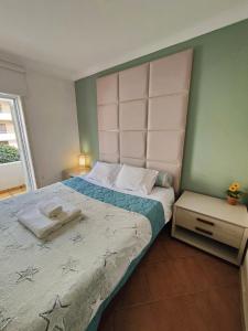 a bedroom with a large bed with a headboard at Vagueira Guest House & Beach Hostel in Aveiro