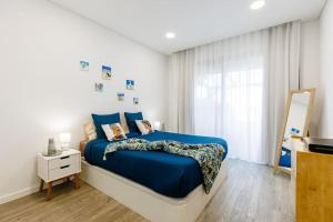 een slaapkamer met een blauw bed en een spiegel bij Jolie maison vue sur l'océan in Funchal