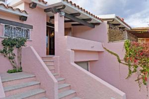 een roze huis met een trap ervoor bij 2 bedrooms property at Porto Taverna 10 m away from the beach with terrace and wifi in Porto Taverna