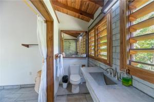 a bathroom with a toilet and a sink and window at Camp Bay Lodge in Roatan
