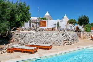 a house with a stone wall next to a swimming pool at Trullo a ll'éra in Ceglie Messapica