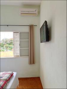 ブロタスにあるSuíte privativa Gigáの窓のある壁にテレビが備わる客室です。