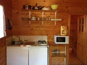eine Küche mit einem weißen Kühlschrank und einer Mikrowelle in der Unterkunft Chalet - Piscine - ef0aac in Porto-Vecchio