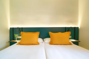 two beds with orange pillows sitting next to each other at Suites & Villas by Dunas in Maspalomas