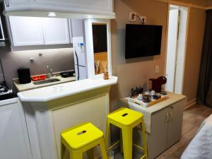 a kitchen with two yellow stools and a sink at Flat Champ's Elysées in Sao Paulo