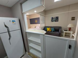 a small kitchen with a refrigerator and a living room at Flat Champ's Elysées in Sao Paulo